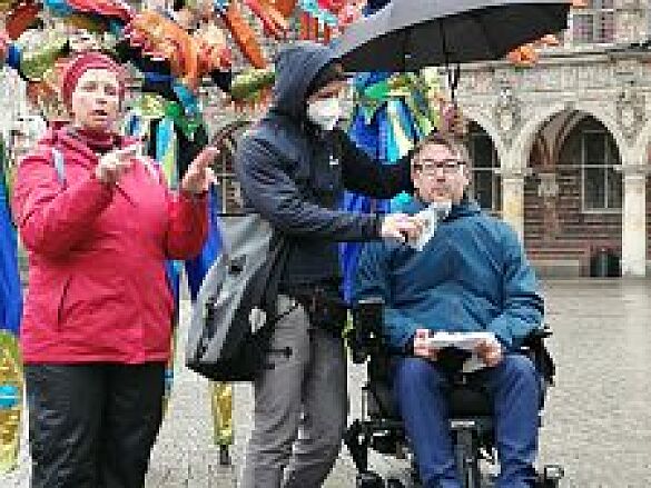 Arne Frankenstein während seiner Rede. Neben ihm steht sein Assistent und hält einen Regenschirm.