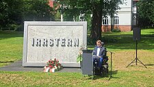 Arne Frankenstein liest seine Rede vor dem Irrstern-Denkmal-Stein im Park